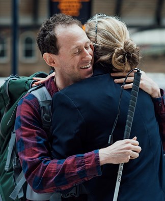 Smiling visually impaired man hugging a friend